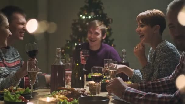 Vrienden feestmaal thuis rond de tafel. Vier Kerstmis. Vijf mensen eten, drinken champagne, praten en lachen. — Stockvideo