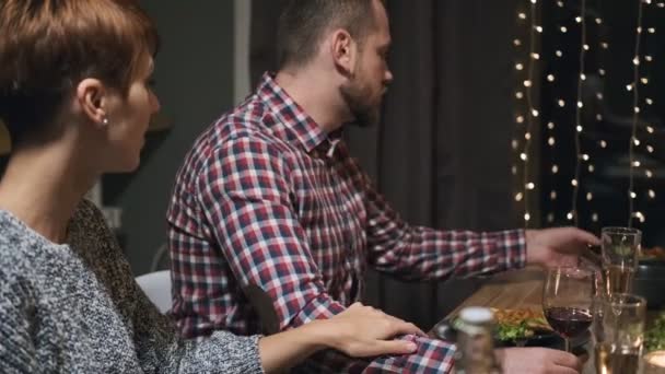 Amigos cena de fiesta en casa alrededor de la mesa. Celebra la Navidad. Cinco personas comen, beben champán, hablan y ríen . — Vídeo de stock