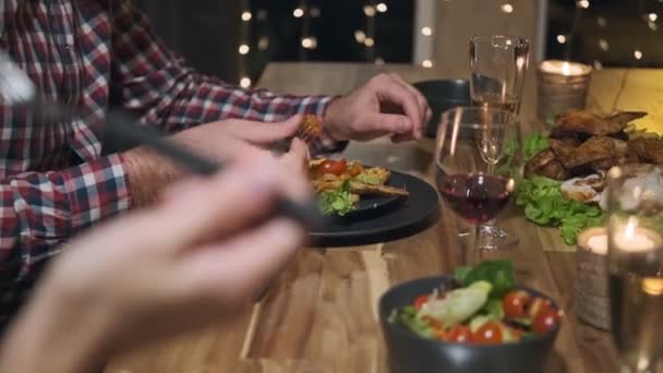 Amigos cena de fiesta en casa alrededor de la mesa. Celebra la Navidad. Cinco personas comen, beben champán, hablan y ríen . — Vídeo de stock