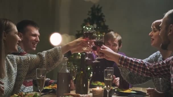 Freunde feiern zu Hause am Tisch. Feiern Sie Weihnachten. Fünf Menschen essen, trinken Champagner, reden und lachen. — Stockvideo