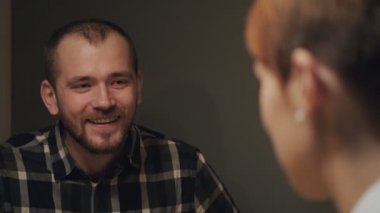 Genç evli bir çift, gündelik giysiler içinde, kadın ve erkek, evlerinde masada oturuyor. Ruh iletişimi ve ev konforu.