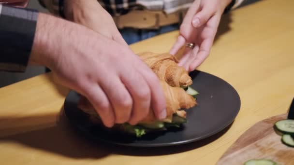 Mladý manželský pár v neformálním oblečení, muž a žena připravují sendviče doma v kuchyni. — Stock video