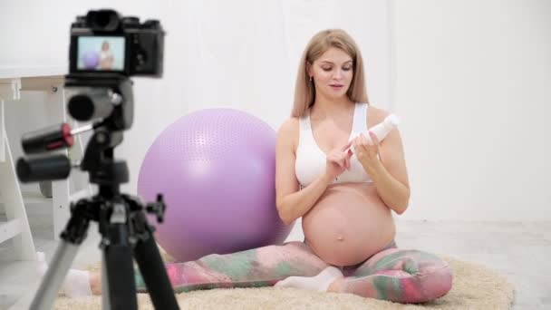 Спортивна вагітна молода жінка-блогер говорить про вправи з м'ячем . — стокове відео