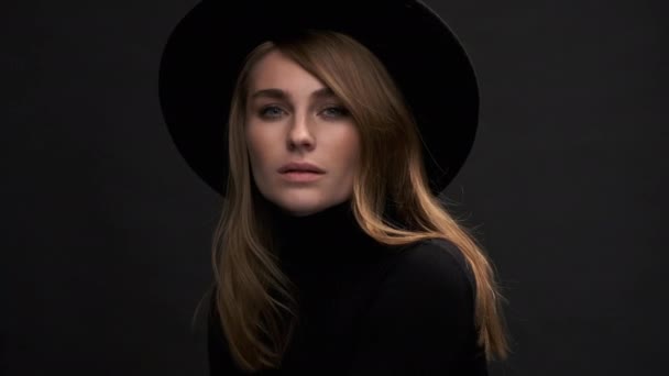 Retrato de una hermosa joven rubia en un sombrero negro con campos y un suéter. Una mujer emocional sensual . — Vídeos de Stock