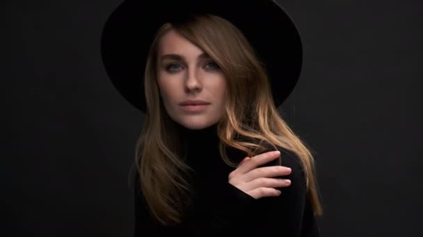Porträtt av en vacker ung blond kvinna i svart hatt med fält och tröja. En sensuell känslomässig kvinna. — Stockvideo