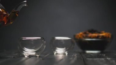 Çay seremonisi. Kadın eli, şeffaf çaydanlıktan cam piala fincanlarına çiçekli sıcak siyah çay doldurur..