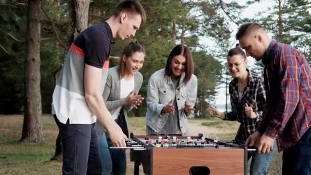 Amigos jogar futebol de mesa ou kicker ao ar livre. Jogadores e fãs se alegram com a vitória . — Vídeo de Stock