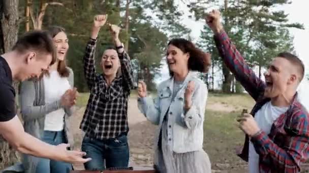 Vänner spelar bordsfotboll eller sparkar utomhus. Spelare och fans glädjas åt segern. — Stockvideo