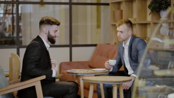 Dos hombres de traje se sientan en un restaurante. Una reunión de negocios. Hombres beben café y charlas . — Vídeo de stock