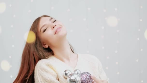 Retrato de uma menina em um fundo branco. Segurando uma caixa de brinquedos para a árvore de Natal . — Vídeo de Stock