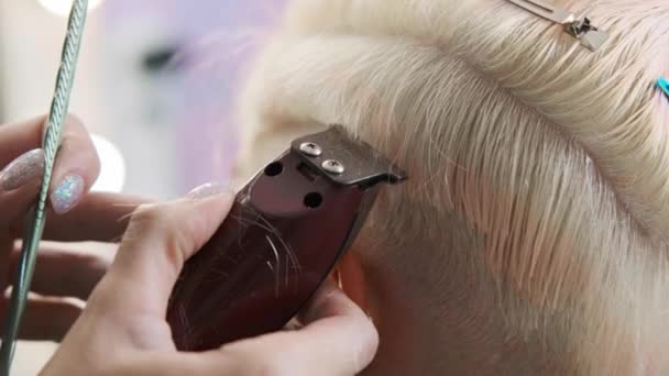 Le coiffeur coupe une cliente blonde avec une tondeuse. Une coupe de cheveux courte pixie et des tempes rasées  . — Video