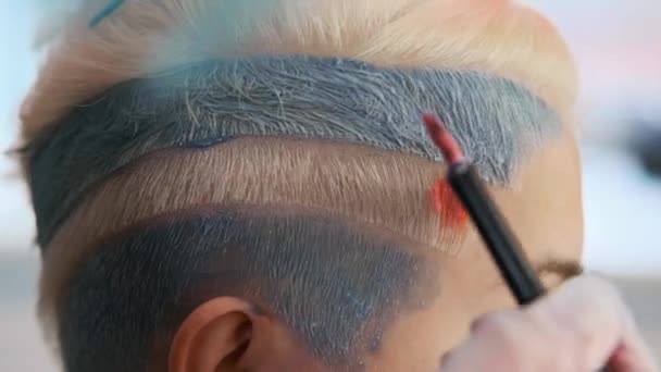 Peluquero colorista pone pintura en el cabello con un cepillo. Un corte de pelo corto, templo afeitado, adorno en el cabello . — Vídeo de stock