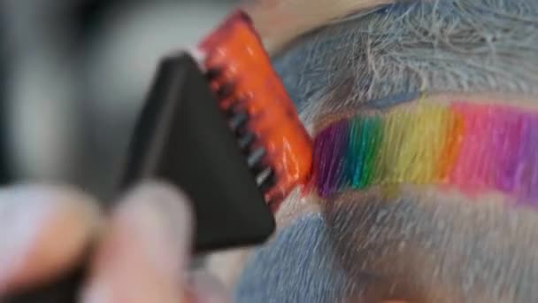 Coloriste coiffeur met de la peinture sur les cheveux avec un pinceau. Une coupe de cheveux courte, temple rasé, ornement sur les cheveux . — Video