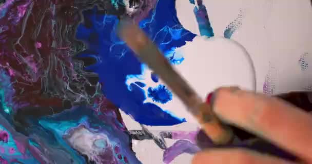 Una artista pinta una pintura abstracta con óleo. Dibujo fluido con varita. Pintura brillante sobre un lienzo blanco . — Vídeo de stock