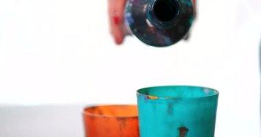 Dişi bir sanatçı çizim için boya hazırlar ve yoğurur. Farklı parlak renkler. Ellerin yakın çekimi.