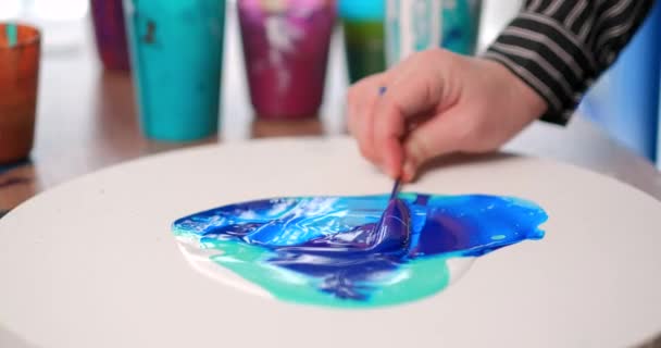 Una donna artista dipinge un dipinto astratto ad olio. Disegno fluido con bacchetta. Pittura brillante su una tela bianca . — Video Stock