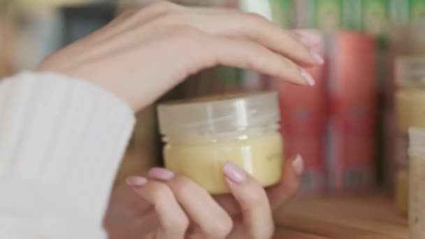 Una mujer elige crema de manos en la tienda. Prueba la crema, untando sobre sí mismo . — Vídeos de Stock