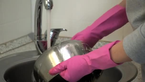 Lastik eldivenli bir kadın, metal bir tencereyi yağlı süngerle yıkıyor.. — Stok video