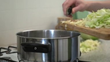 Rus lahana çorbası pişiriyorum. Bir kadın kesme tahtasıyla sebze kesiyor. Ev mutfağında yemek yapmak..