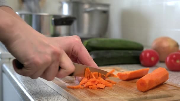 Uma cozinheira fêmea corta cenouras em uma tábua de corte para sopa. Cozinhar em casa . — Vídeo de Stock