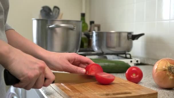 A női szakács szeleteli a paradicsomot a vágódeszkán, és hozzáadja a leveshez. Orosz káposztalevest főzök. Egy nő zöldséget szeletel egy vágódeszkán.. — Stock videók