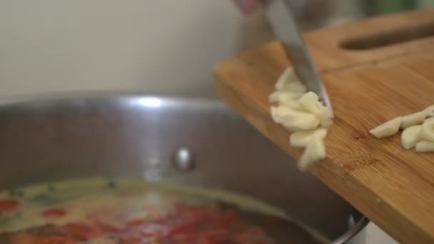 Une cuisinière coupe l'ail sur une planche à découper. Cuisiner la soupe au chou russe. Une femme coupe des légumes sur une planche à découper . — Video