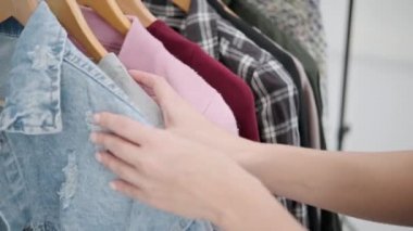 Beyaz odadaki genç ve çekici bir kadın deneyip kıyafet seçiyor. Aynaya bakar ve kıyafetleri karşılaştırır. Soyunma odası ya da soyunma odası..