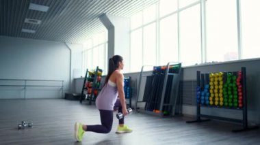 Spor kıyafetleri giymiş, spor salonunda dambılları olan güzel bir esmer kadın..