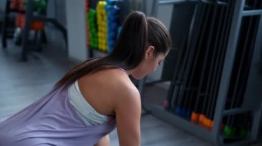 Spor kıyafetleri giymiş, spor salonunda dambılları olan güzel bir esmer kadın..