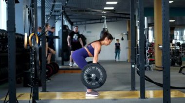 Spor giyimli, güzel, atletik, esmer bir kadın spor salonunda halterle egzersiz yapıyor..