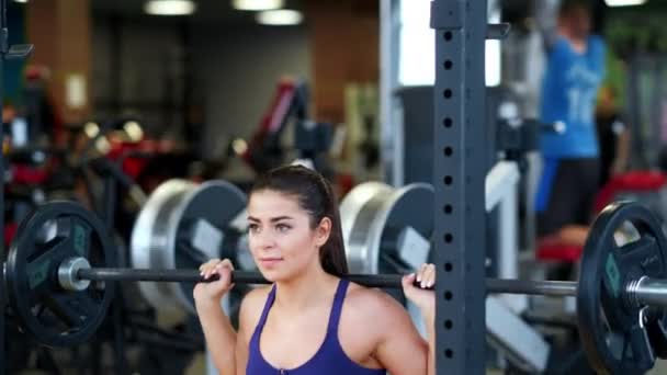 Krásná sportovní mladá brunetka žena ve sportovním oblečení v tělocvičně provádí cvičení s činkou. — Stock video