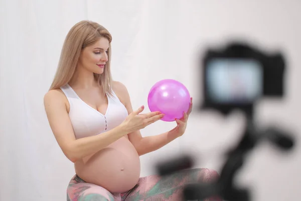Спортивная беременная молодая женщина блогер говорит о мяч упражнения . — стоковое фото