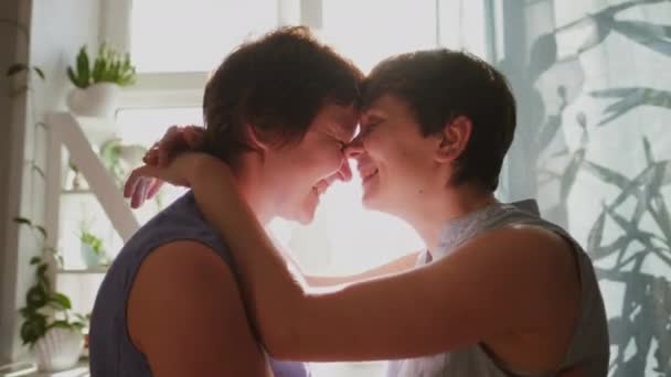 Two young women hug and kiss at home. Casual clothing. Lesbian couple, homosexual relations, same-sex love. — Stock Video