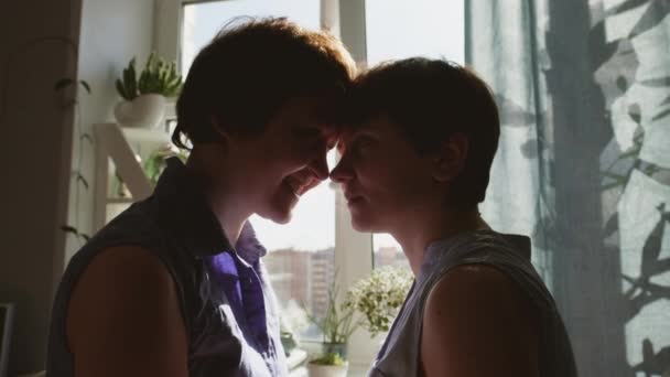 Twee jonge vrouwen knuffelen en zoenen thuis. Vrijetijdskleding. lesbisch paar, homoseksuele relatie, liefde tussen man en vrouw. — Stockvideo