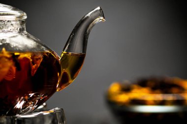 Siyah arka plandaki çay setinin yatay fotoğrafı. Cam şeffaf çaydanlık ve bardak. Siyah yaprak çayı..