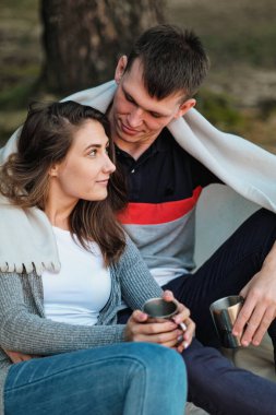 Birbirine aşık bir çift gün batımında nehir kenarında oturur. Sarılırlar, ekoseye sarınırlar ve metal bir bardaktan çay içerler..