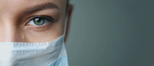 Beyaz cüppeli, maskeli ve eldivenli bir kadın doktor. Yüzü yakın plan. Doktor ağlar ve dua eder. Gözyaşları. Salgın ve virüs salgını. Coronavirus covid-19. Boşluğu kopyala.