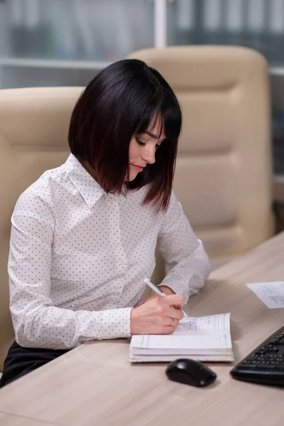 Portret van een jonge mooie vrouw, een kantoormedewerker in een wit shirt. Een vrouw werkt op een computer.. — Stockfoto