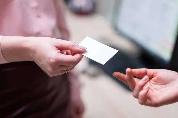 Bir kadın başka bir kadına kartvizit verir. İki elin yakın çekimi..