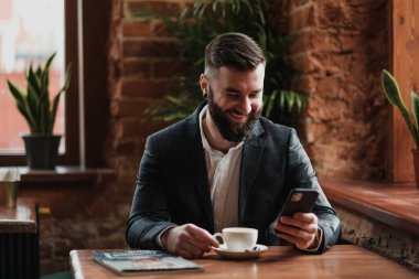 Pencerenin karşısındaki restoranda yakışıklı, şık, sakallı bir adam, Kavkuzets Chdmt. Dergi okuyor, kahve içiyor..