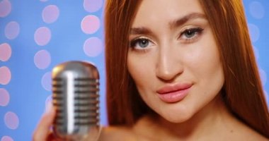 Uzun saçlı, pullu bir gece elbisesi içinde güzel, genç ve seksi bir kadın. Klasik bir mikrofonda şarkı söyleyen, dans eden ve gülümseyen bir kız..