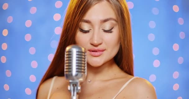 Una bella giovane donna sexy con i capelli lunghi in un abito da sera con paillettes. Ragazza canta sul palco con un microfono vintage, balli e sorrisi . — Video Stock