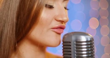 Uzun saçlı, pullu bir gece elbisesi içinde güzel, genç ve seksi bir kadın. Klasik bir mikrofonda şarkı söyleyen, dans eden ve gülümseyen bir kız..