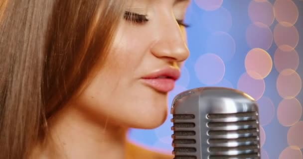 Una bella giovane donna sexy con i capelli lunghi in un abito da sera con paillettes. Ragazza canta sul palco con un microfono vintage, balli e sorrisi . — Video Stock