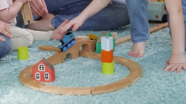 Çocuklar ve ebeveynler evin zemininde tahta oyuncaklarla oynarlar.. — Stok video