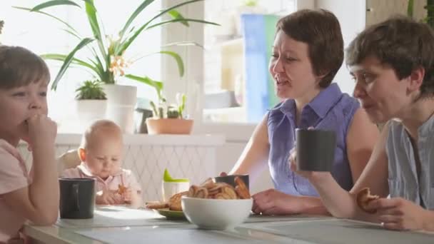 Una familia lesbiana homosexual con dos hijos y madres se sienta en la cocina en una mesa y desayuna. Estilo de vida . — Vídeo de stock