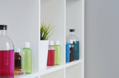 Rafta farklı renkte sıvı içeren birçok farklı şişe ve test tüpleri duruyor. Eczane.