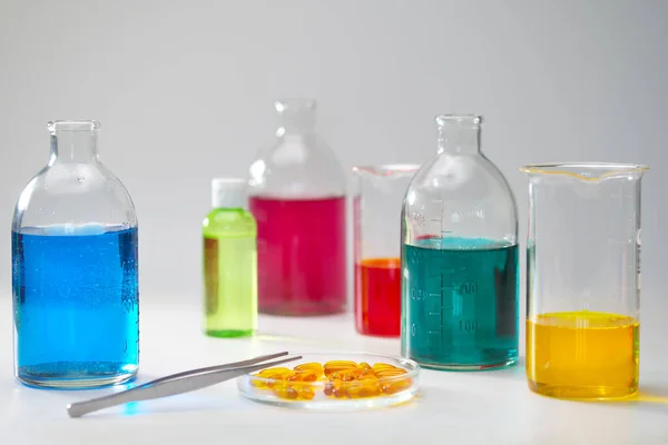 Γυάλινα μπουκάλια και φιάλες διαφόρων μεγεθών με υγρά διαφορετικών χρωμάτων στο φόντο. Χημικό εργαστήριο. — Φωτογραφία Αρχείου