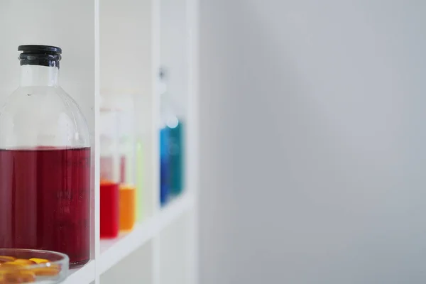 Πολλές διαφορετικές φιάλες και δοκιμαστικοί σωλήνες με υγρά διαφορετικών χρωμάτων στέκονται στο ράφι. Φαρμακείο. — Φωτογραφία Αρχείου