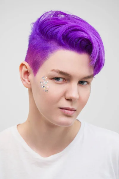 Portrait of a young attractive woman in a white T-shirt on a white background. Purple-colored short hair.